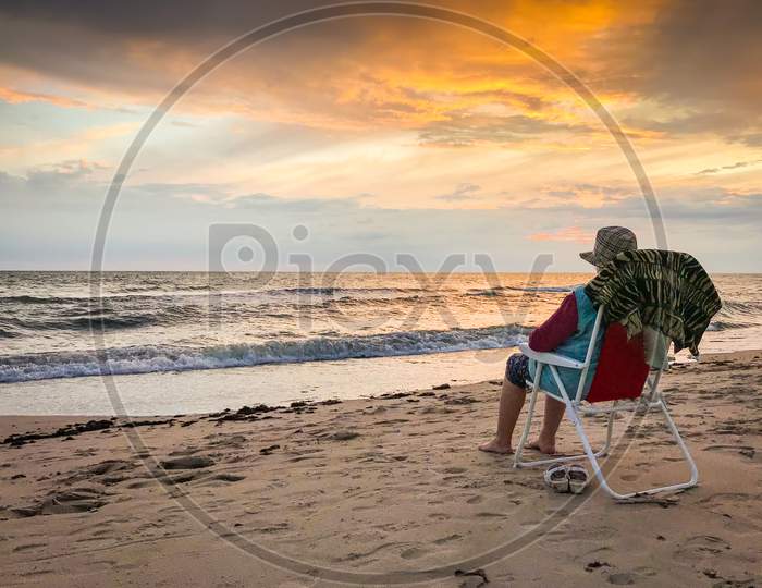 Elderly Woman Sitting On Foldable Chair On Palanga Beach Enjoy Watching Sunset And Sea In Calm Tranquil Evening. Lithaunia Summer Holiday Vacation.
