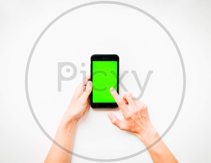 Females Hand Shows Mobile Smartphone With Green Screen In Vertical Position Isolated On White Background With Finger Tap Screen. Mock Up Mobile Technology Ad Concept.