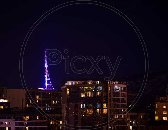 Tbilisi, Georgia - 17Th April, 2021: Tbilisi Tv Communication Tower Illuminated At Night. View Georgia Capital And House Buildings At Night Concept Background.