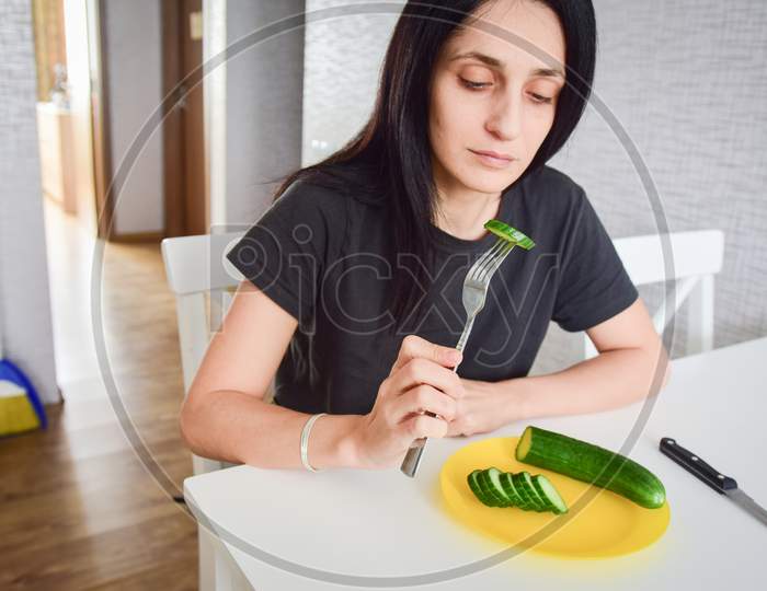 Portrait Young Attractive Caucasian Woman Eat Cucumber In Kitchen Slowly For Breakfast On Diet