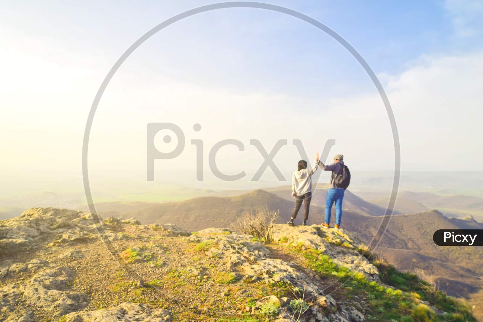 Caucasian Couple Enjoy Panorama Together With Hands Up Clapping Outdoors.Success, Freedom And Happy Travels Concept.