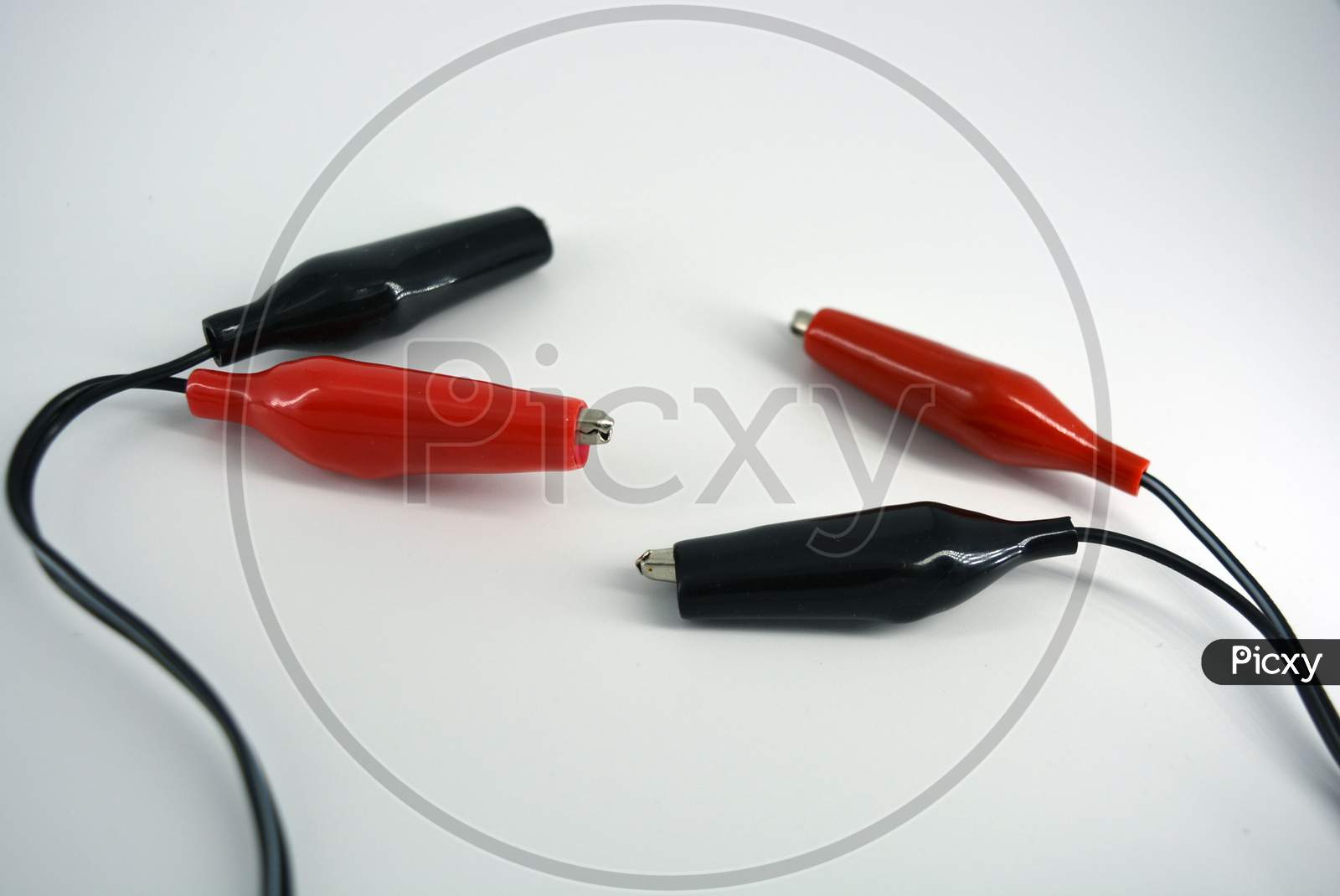 Black wire with red and black insulation, rubber and metal crocodiles for lining to the wire located on a white background.