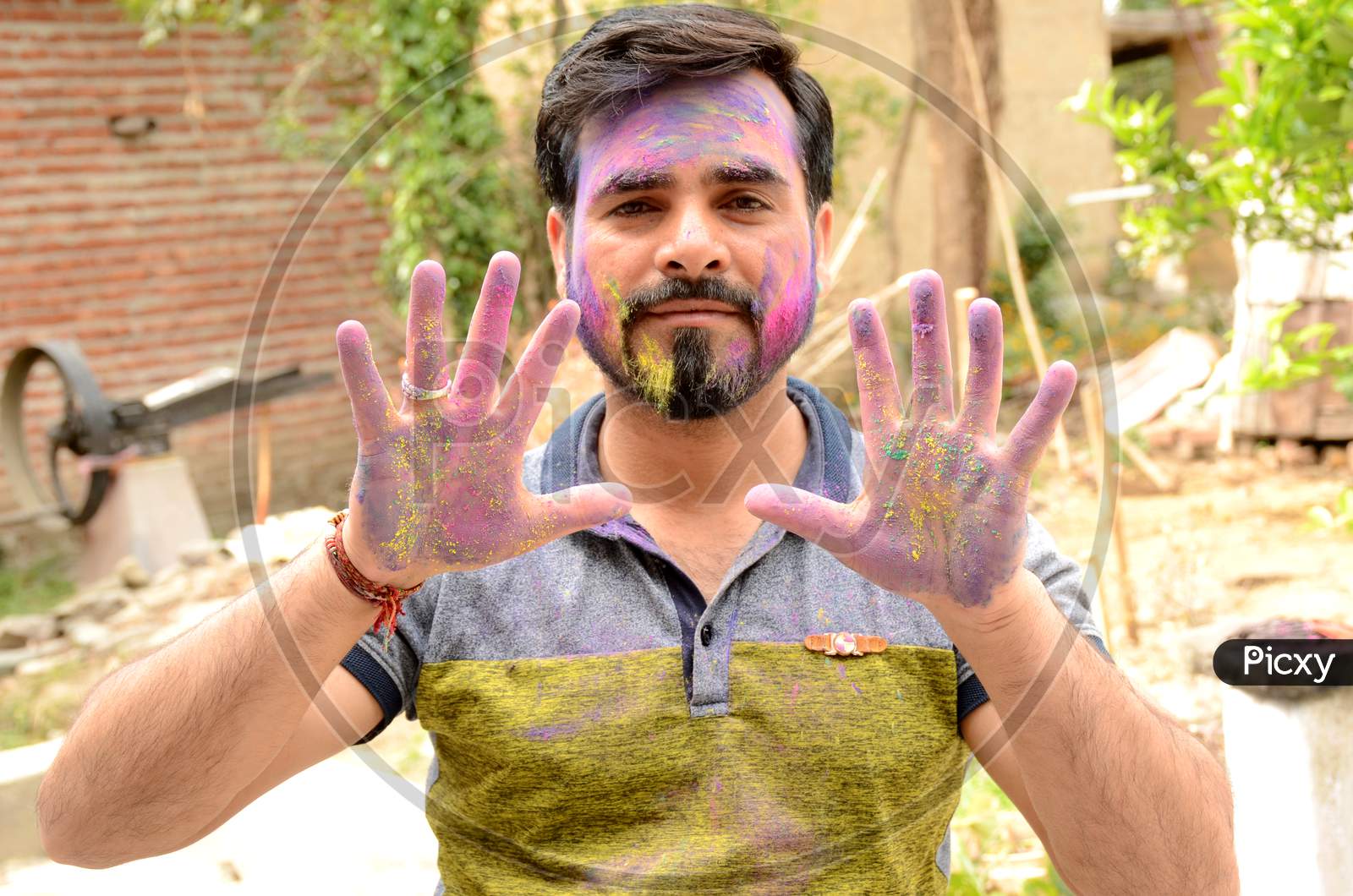 The Young Man Paint On The Face With Hand Over Out Of The Focus Green Brown Background.