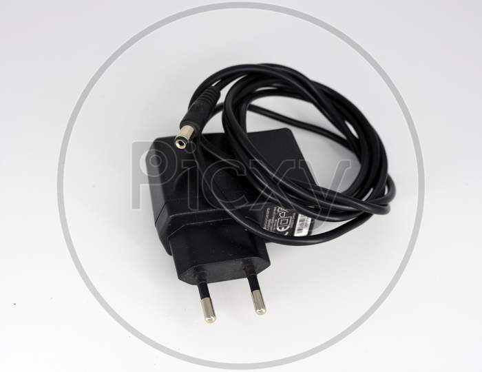 Black metal plug, power supply for connecting and charging the phone into a reinstate 220 in a white plastic background.