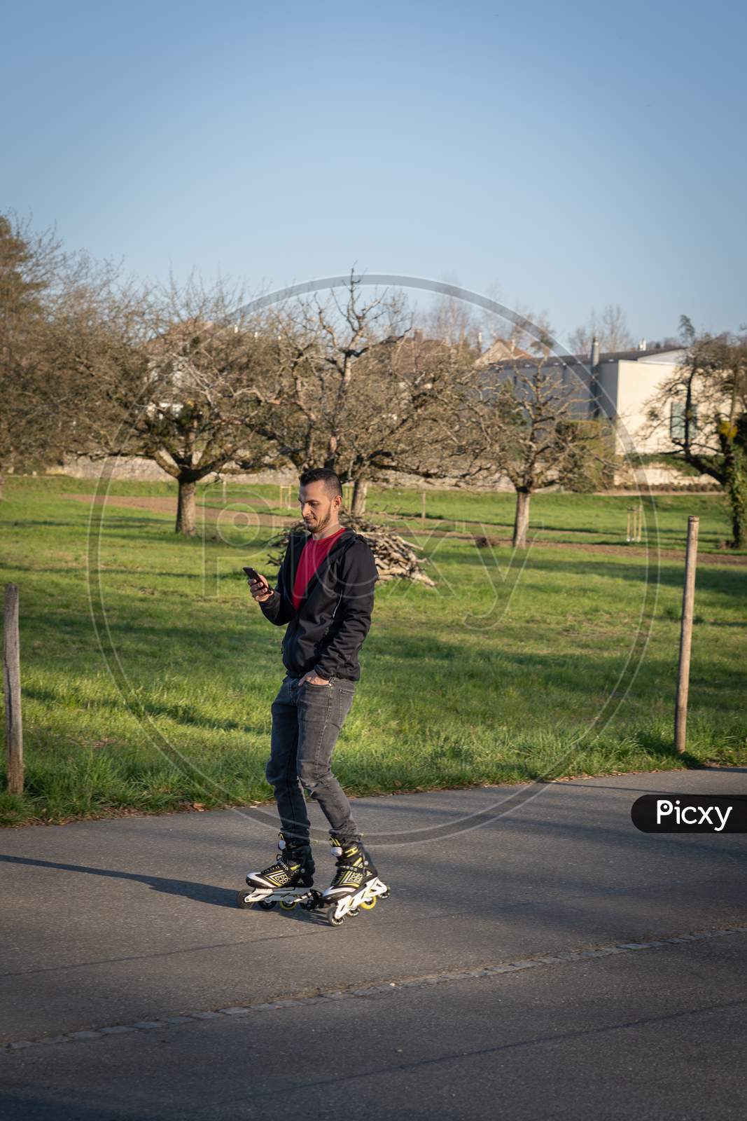Young Man On Roller Blade Looking At His Phone. Technologie In Nature.