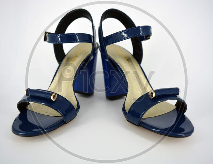 Beautiful and bright female blue lacquer sandals made of genuine leather on a wide heel with a golden insole located on a white background.