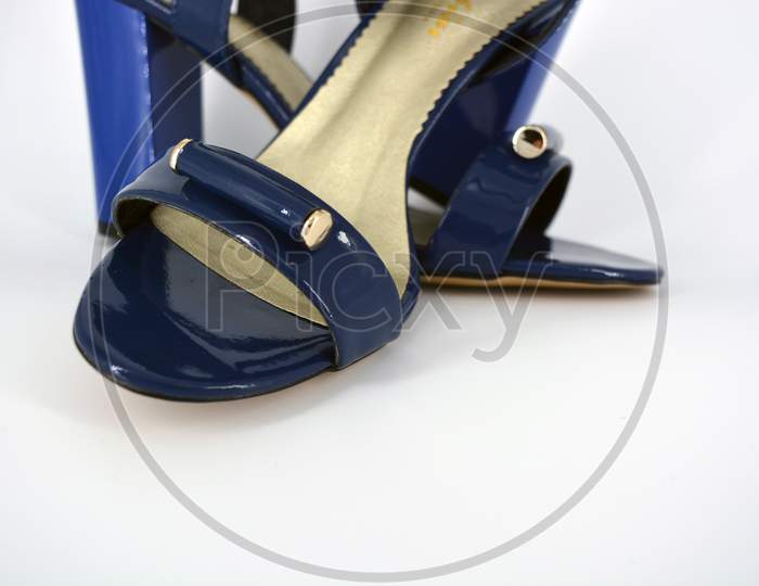 Beautiful and bright female blue lacquer sandals made of genuine leather on a wide heel with a golden insole located on a white background.
