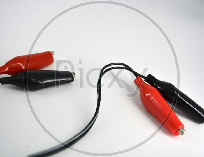 Black wire with red and black insulation, rubber and metal crocodiles for lining to the wire located on a white background.