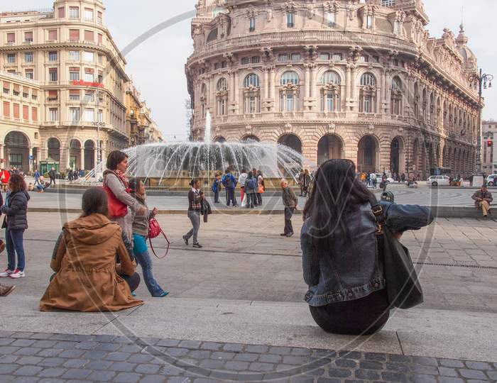 Genoa, Italy - March 16, 2014: Tourists Visiting Piazza De Ferrari Main Square And Fountain