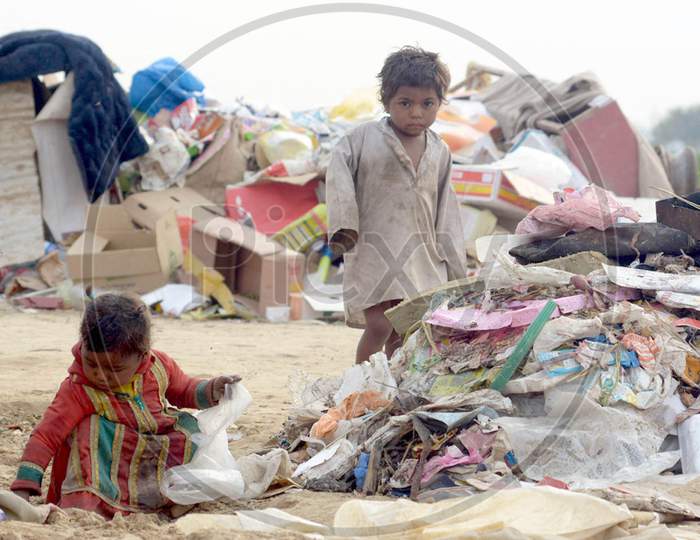 Two Sibling Rag pickers Are Sorting Out Reusable Items From A Heap Of Garbage Near A Dump.