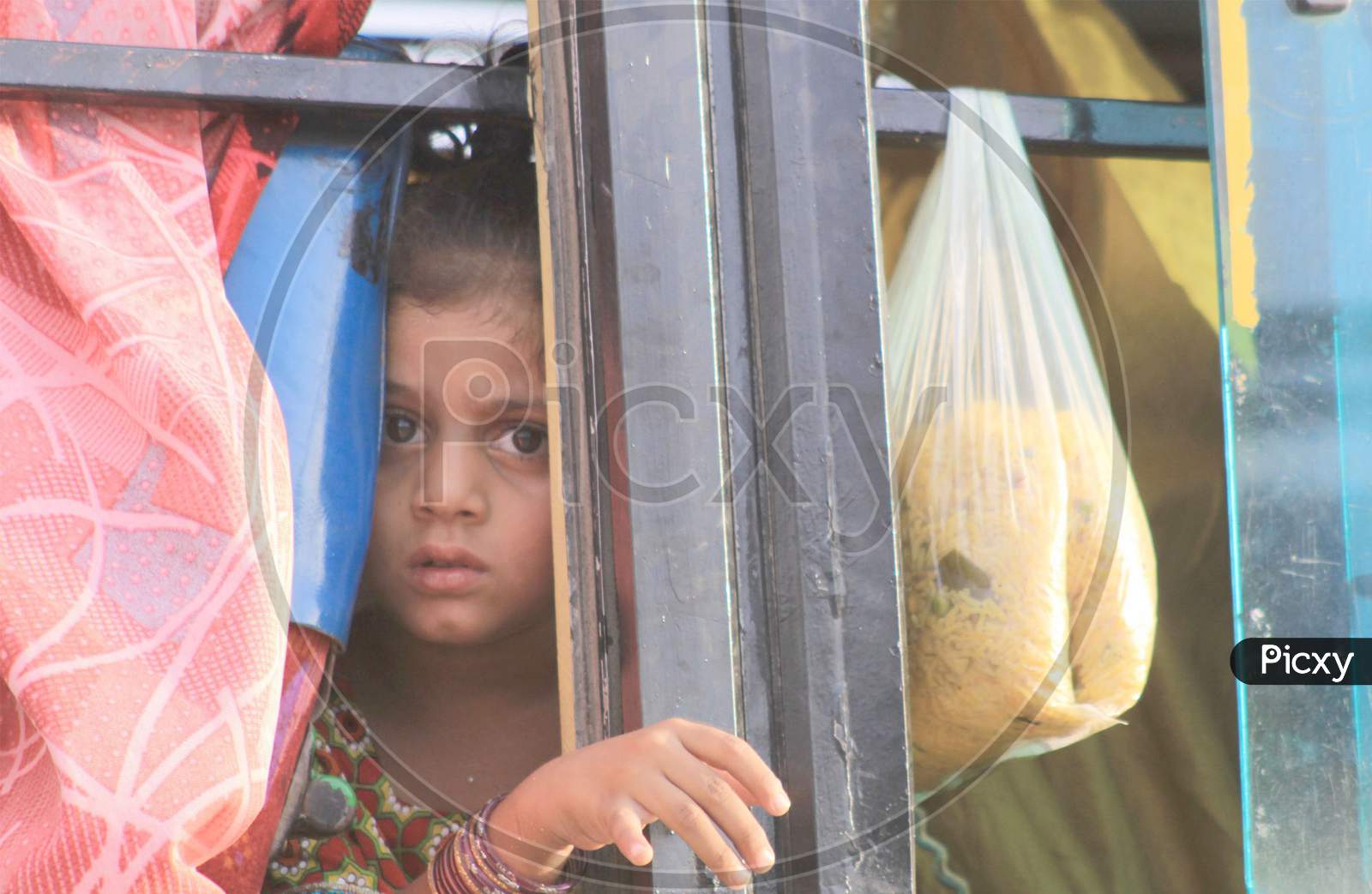 Food Security Gets Grave: A Baby Girl Peeps Out Of The Bus After Collecting Food For The Family From The Shrine Of Bari Imam In Islamabad.