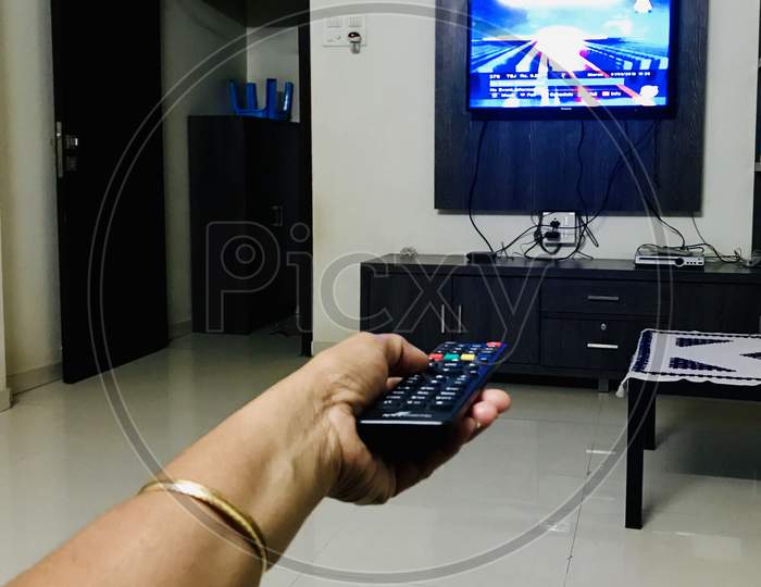 Hand using remote control for changing television channel