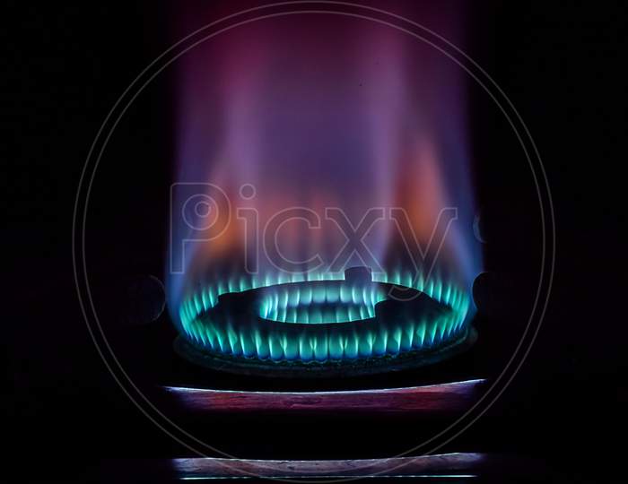 Stock Photo Of Gas Burner With Blue And Purple Flame On Kitchen Stove In Dark Black Background, Focus On Object.