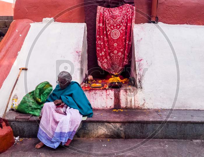 Guwahati, Assam, India - January 2018: An Elderly Indian Woman Sitting Beside A Shrine In The Ancient Hindu Kamakhya Temple Complex.
