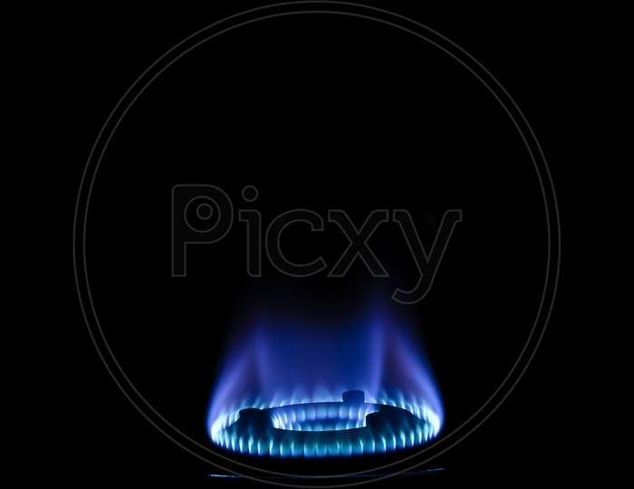 Stock Photo Of Gas Burner With Blue Flame On Kitchen Stove In Dark Black Background, Focus On Object.