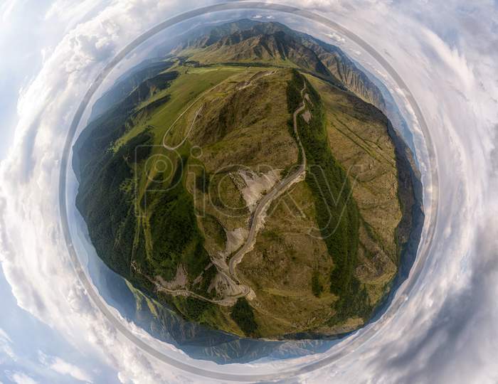 Helicopter Drone Shot. Aerial Photography Of A Mountain,  Green Field, Road, Small Village And Forest. Panoramic City 360  Shot From Above