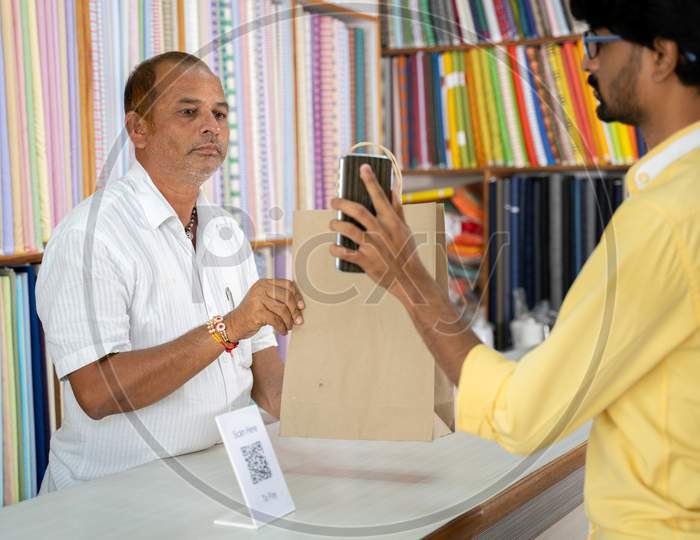 Customer Using Digital Payment Method Scan To Pay At Cloth Store To Send Money And Shoing To Shopkeeper - Concept Of Digital Or Contactless Payment, E-Transfer, Technology And Lifestyle.