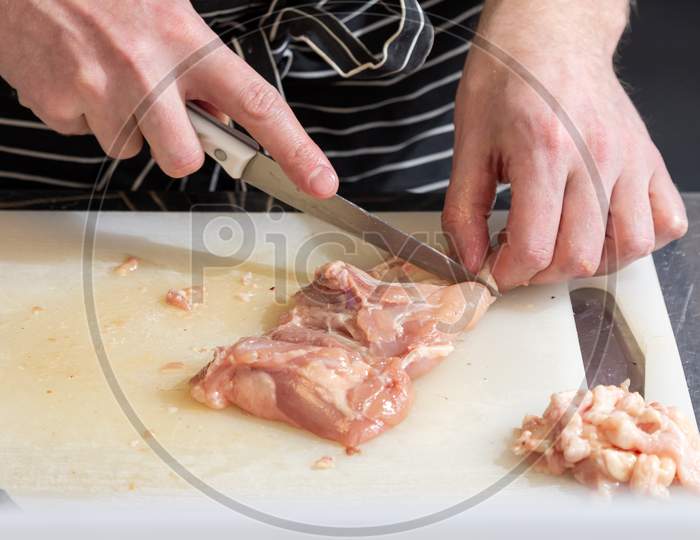 Step By Step Cooking Chicken: A Man In An Apron Cuts Slices With A Knife On A Wooden Board.