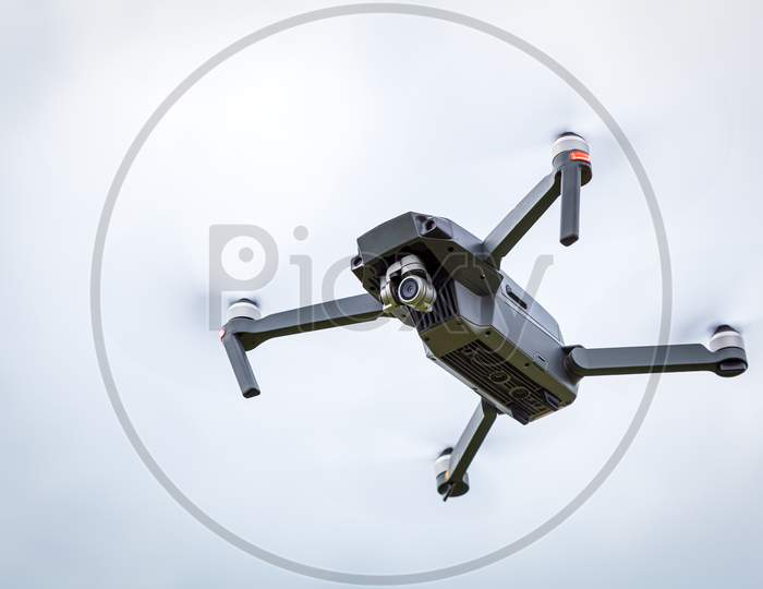 Close Up Of The Dron Helicopter With A Camera. Quadcopter Isolated On  Sky Background