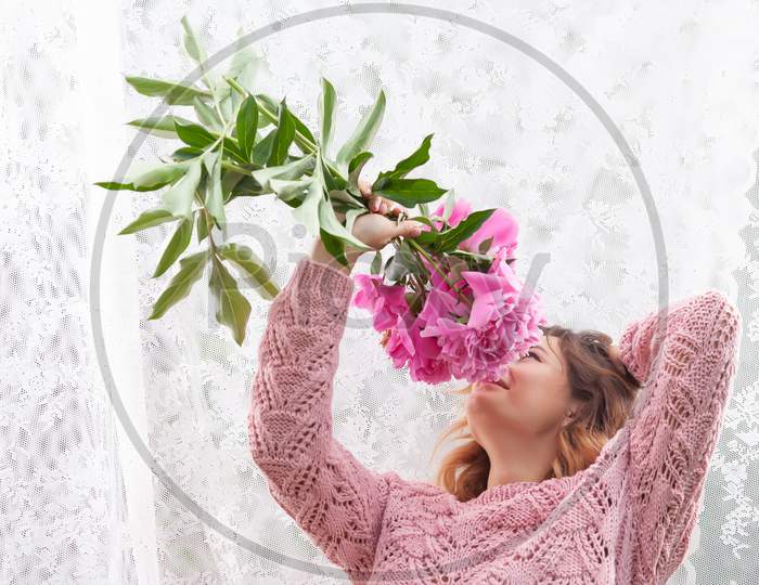 Portrait Of A Beautiful Young  Caucasian Woman 20 Years Old Model In    Brown Knit Sweater With Natural Make-Up And Pink Flower Peonies Posing On White Isolated Background
