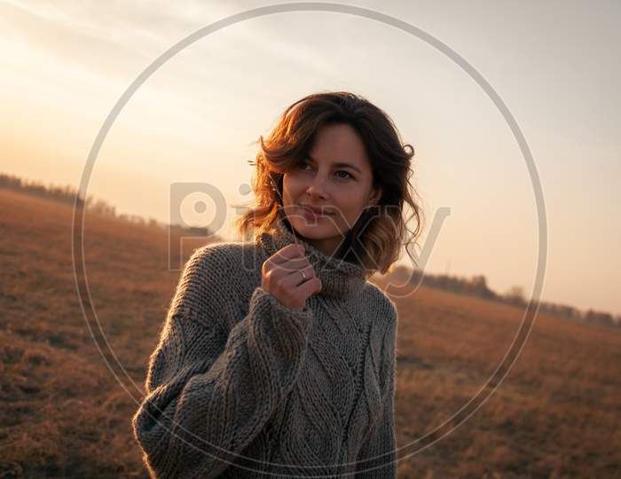 Fashion Lifestyle Portrait Of Young Trendy Woman Dressed In Brown Knit Sweater Made Of Natural Wool And Jeans Laughing, Smiling, Posing And  Against A White Wall In The Street.Portrait Of Joyful Woman