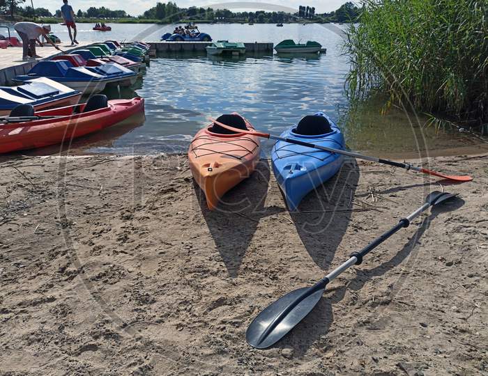 Krakow, Poland - May 05, 2021: Wide Angle Shot Of Couple Of Kayak For Rent Kept At Dock With It'S Paddle In The Man Made Lake Lagoon Named Kryspinow Located In The District Of Gmina Liszki