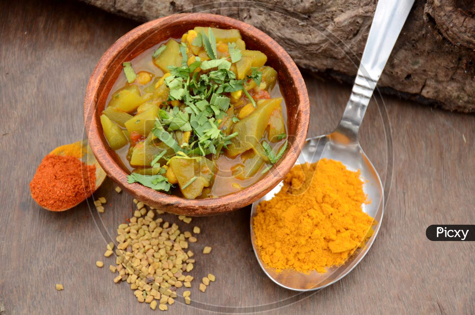 The Round Gourd Made Vegetable In The Wooden Bowl With Turmeric,Red Chilly Powder,And Greek, On The Brown Wooden Background.