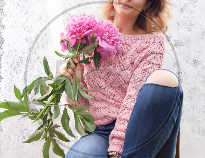 Portrait Of A Beautiful Young  Caucasian Woman 20 Years Old Model In    Brown Knit Sweater With Natural Make-Up And Pink Flower Peonies Posing On White Isolated Background