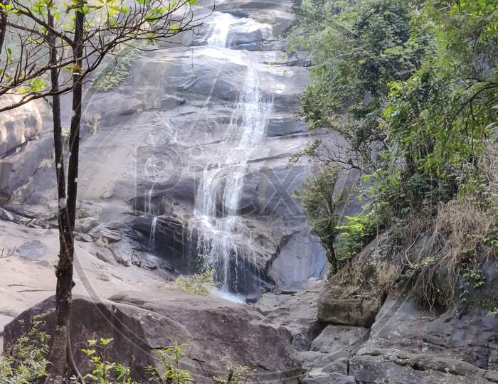View Of Water Falls Over The Rocks In The Forest