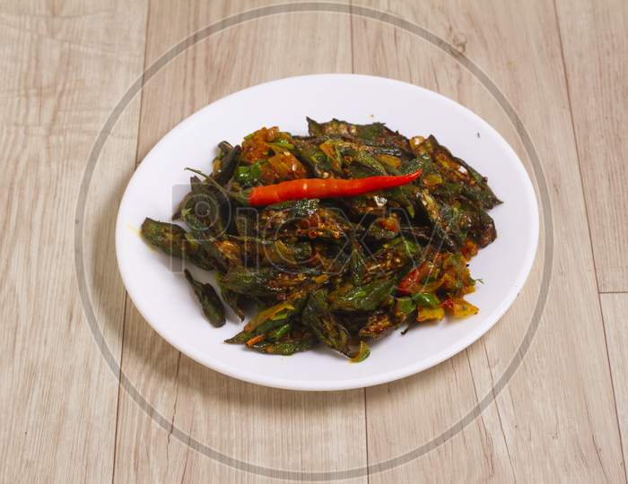 Indian Style Masala Sabji Or Sabzi Of Fried Bhindi Or Okra Also Known As Ladyfinger, Served In A Bowl Over Wooden Background. Selective Focus