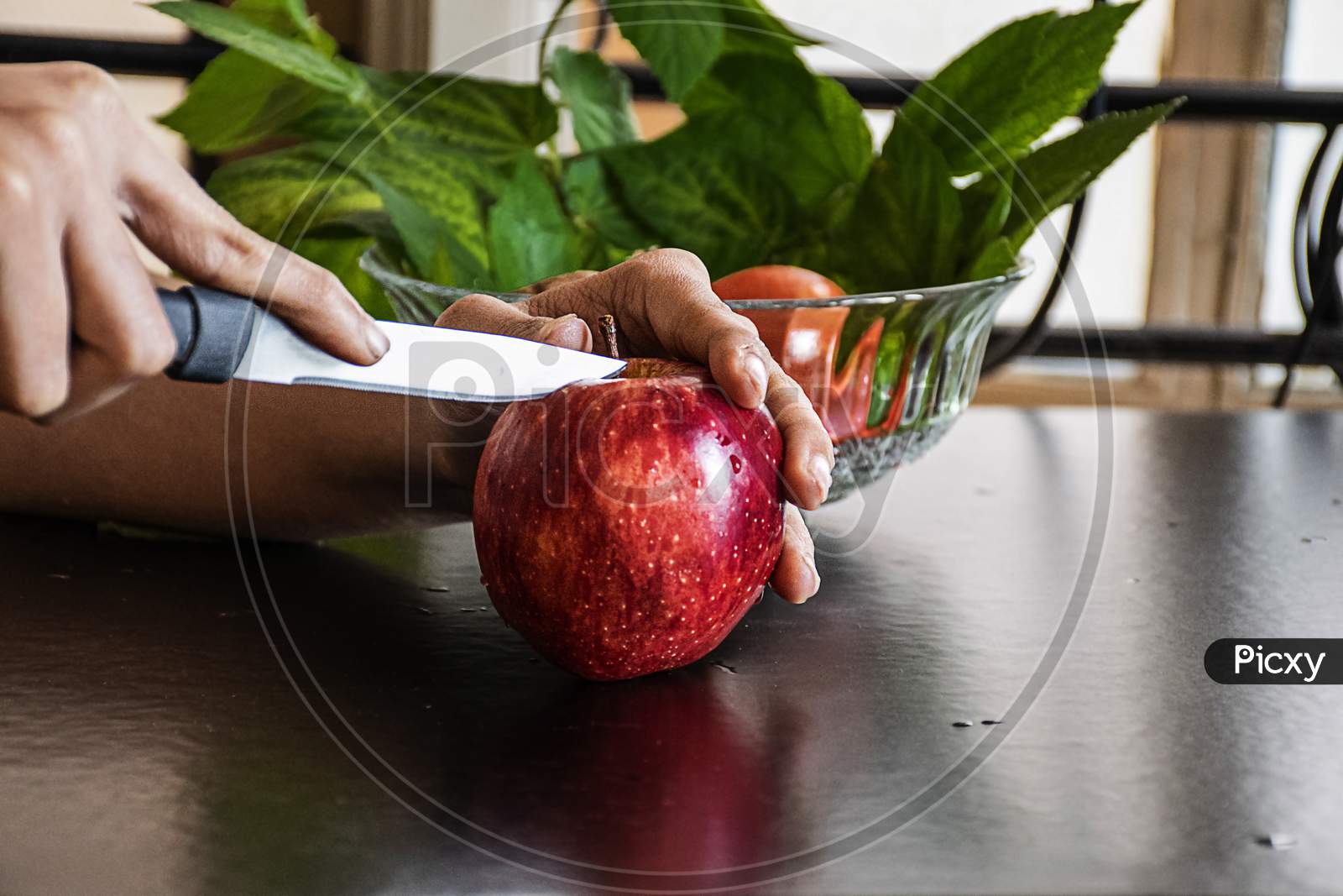 Stock Photo Of A Women Hand Cutting Fresh Red Apple In The Morning For Breakfast, Apple Kept On Black Color Table .