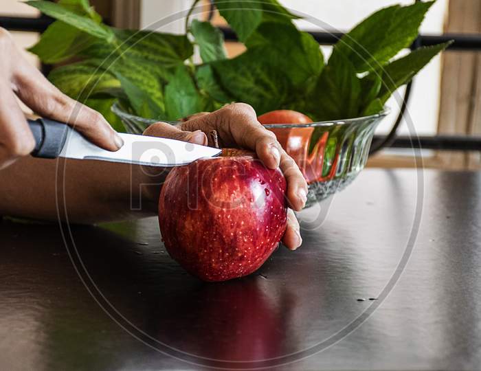 Stock Photo Of A Women Hand Cutting Fresh Red Apple In The Morning For Breakfast, Apple Kept On Black Color Table .