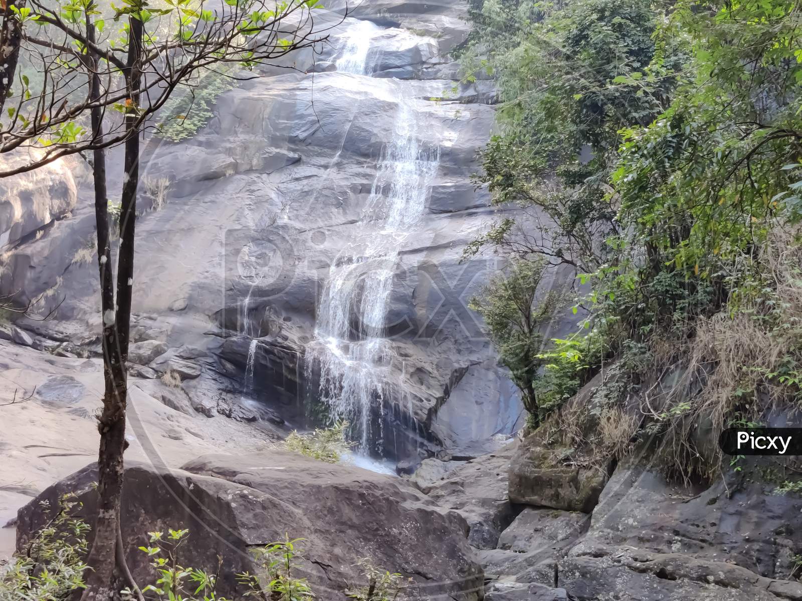 View Of Water Falls Over The Rocks In The Forest