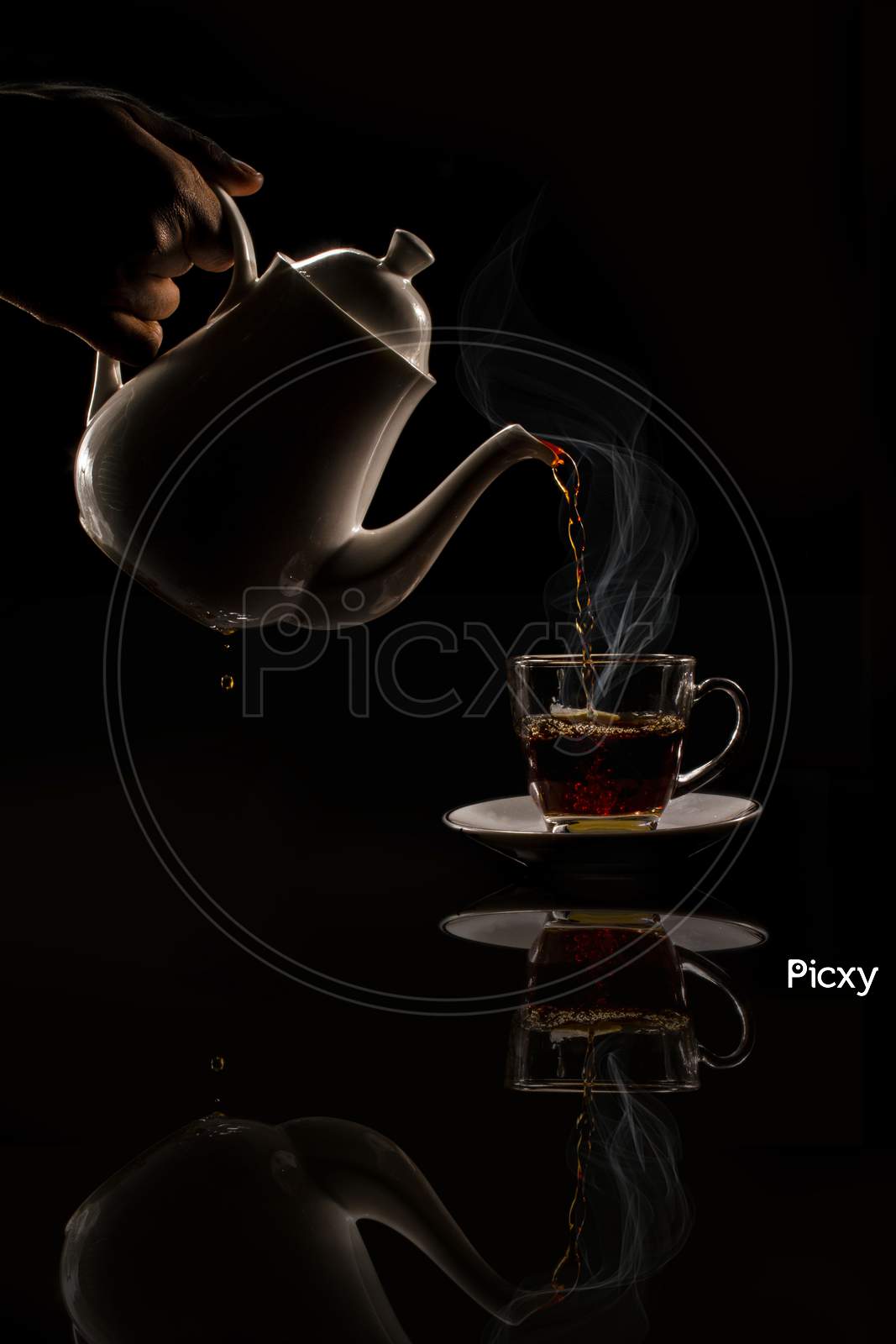 Pouring Black Hot Tea Into The Cup Stock Photo.On Black Background.