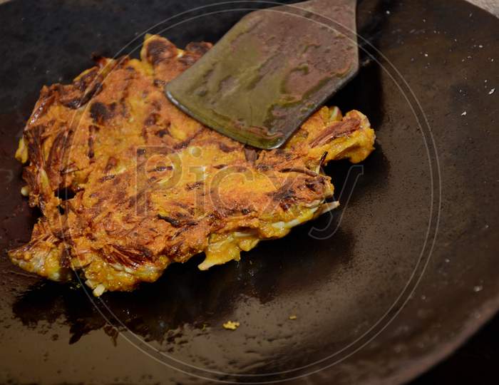 The Yellow Tree Flower Fried Made Veg With Metal Dark Vessel.
