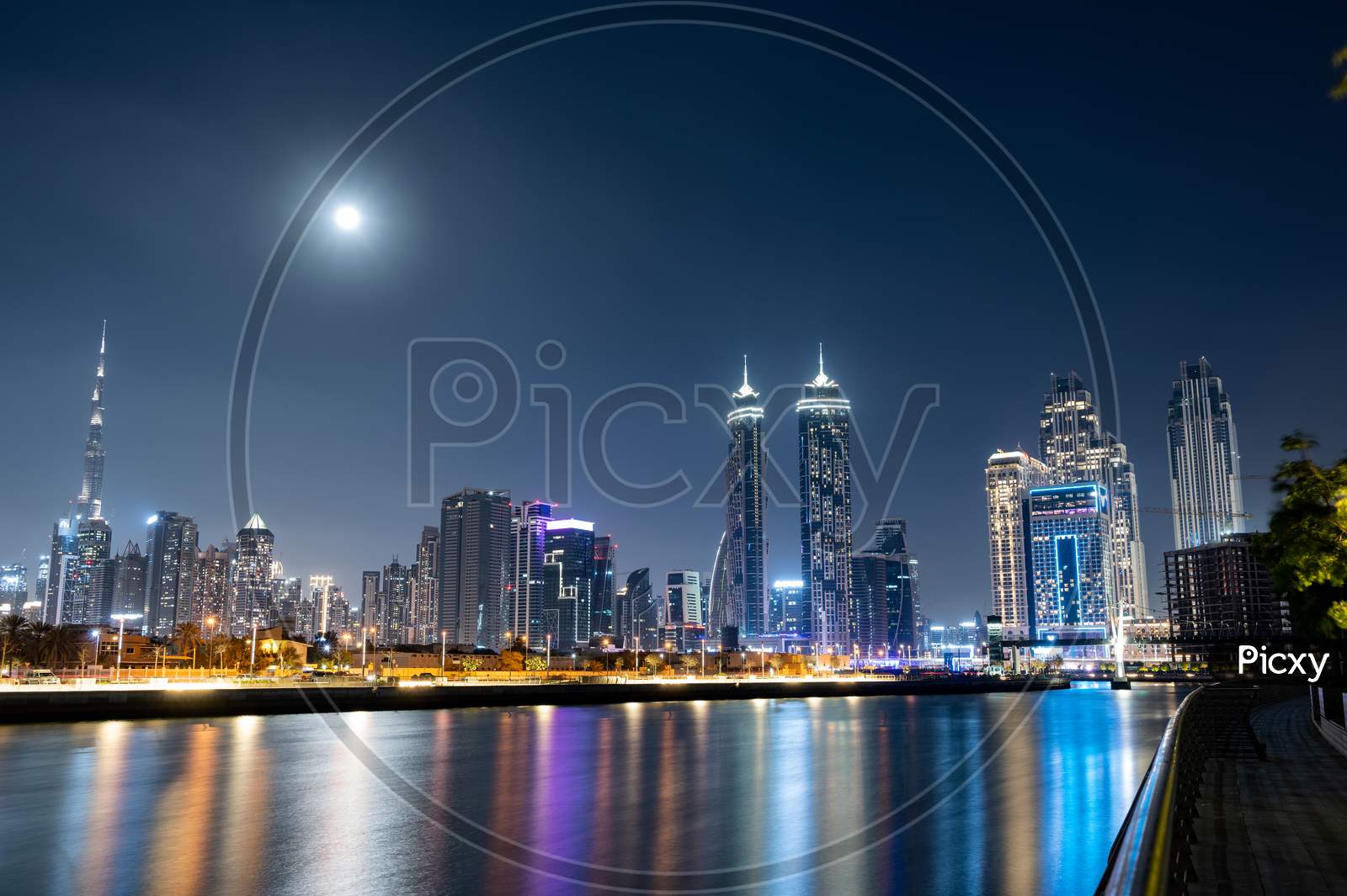 Feb 26Th , 2021 Dubai, Uae. Panoramic View Of The Illuminated Burj Khalifa With Other Skyscrapers Throwing Beautiful Reflections On Water Captured From The Dubai Canal Boardwalk, Dubai, Uae.
