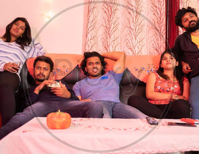Concept Of Lazy Weekend Or Boring Movie - Group Of Young Friends Watching Uninteresting Web Series While Sitting On Sofa At Home During Holiday Vacation.