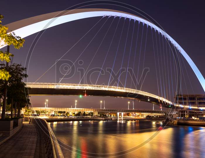 Beautiful View Of The Illuminated Tolerance Bridge Captured At Night Time From The Dubai Canal Boardwalk, Dubai, Uae.