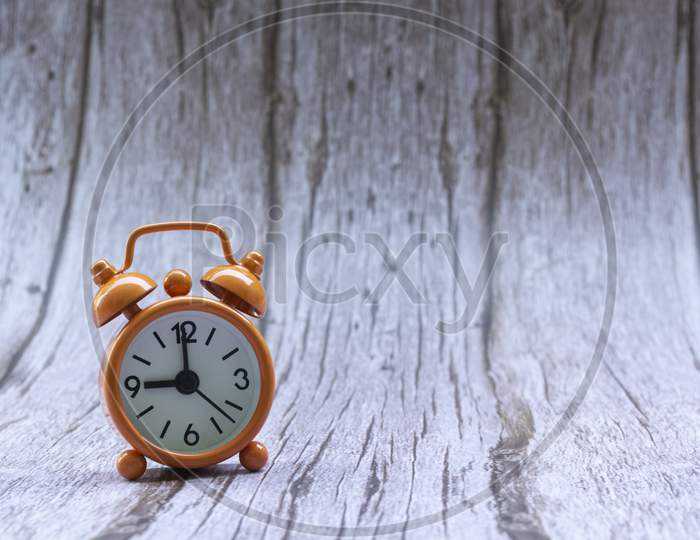 Orange Old Retro Style Alarm Clock On Wooden Background