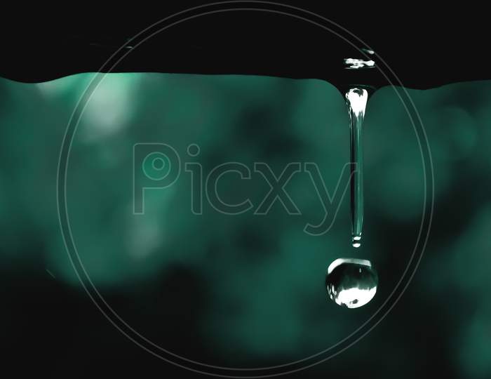 Water drop falling during monsoon on a rainy day with green background