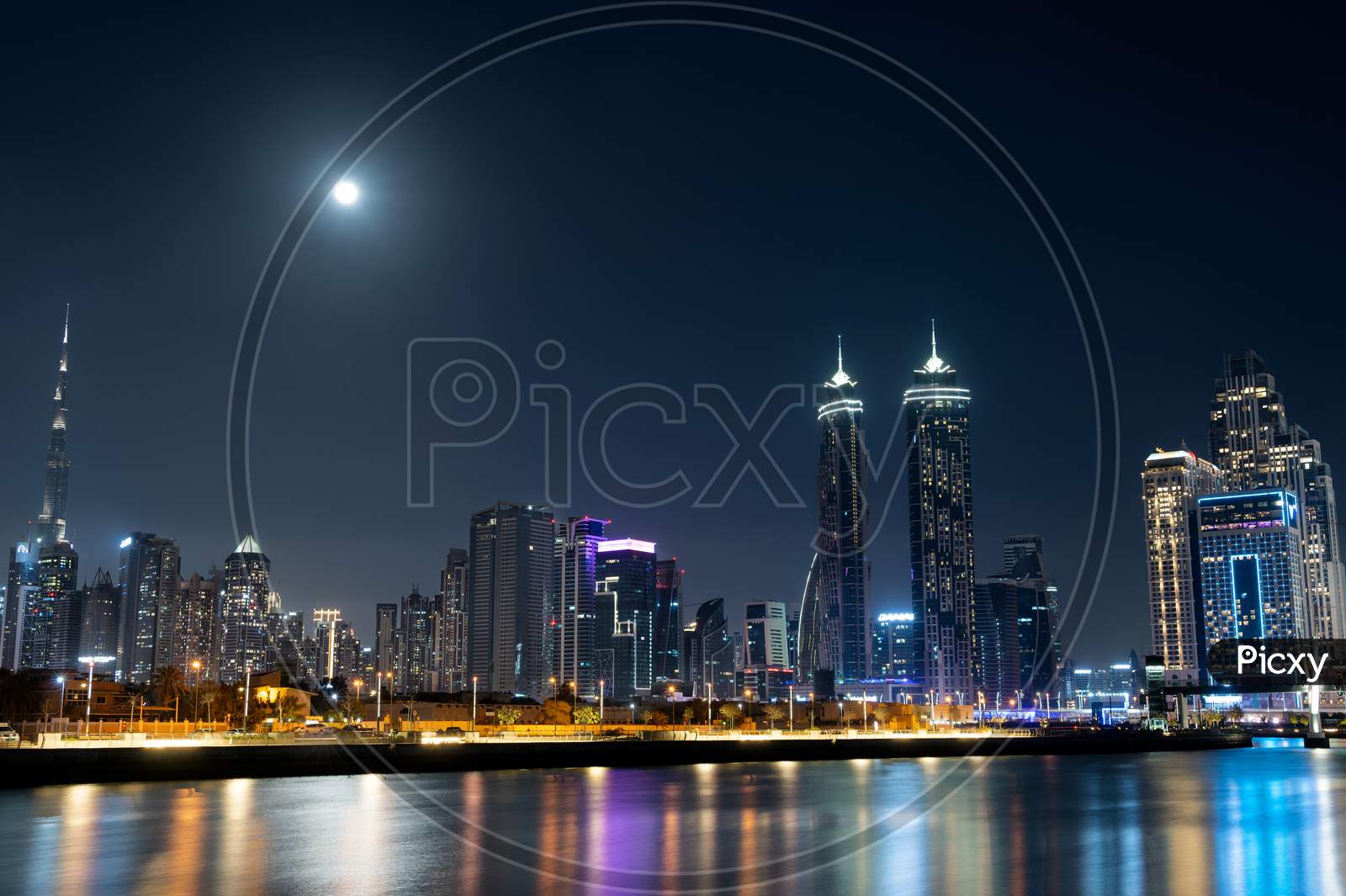 Feb 26Th , 2021 Dubai, Uae. Panoramic View Of The Illuminated Burj Khalifa With Other Skyscrapers Throwing Beautiful Reflections On Water Captured From The Dubai Canal Boardwalk, Dubai, Uae.