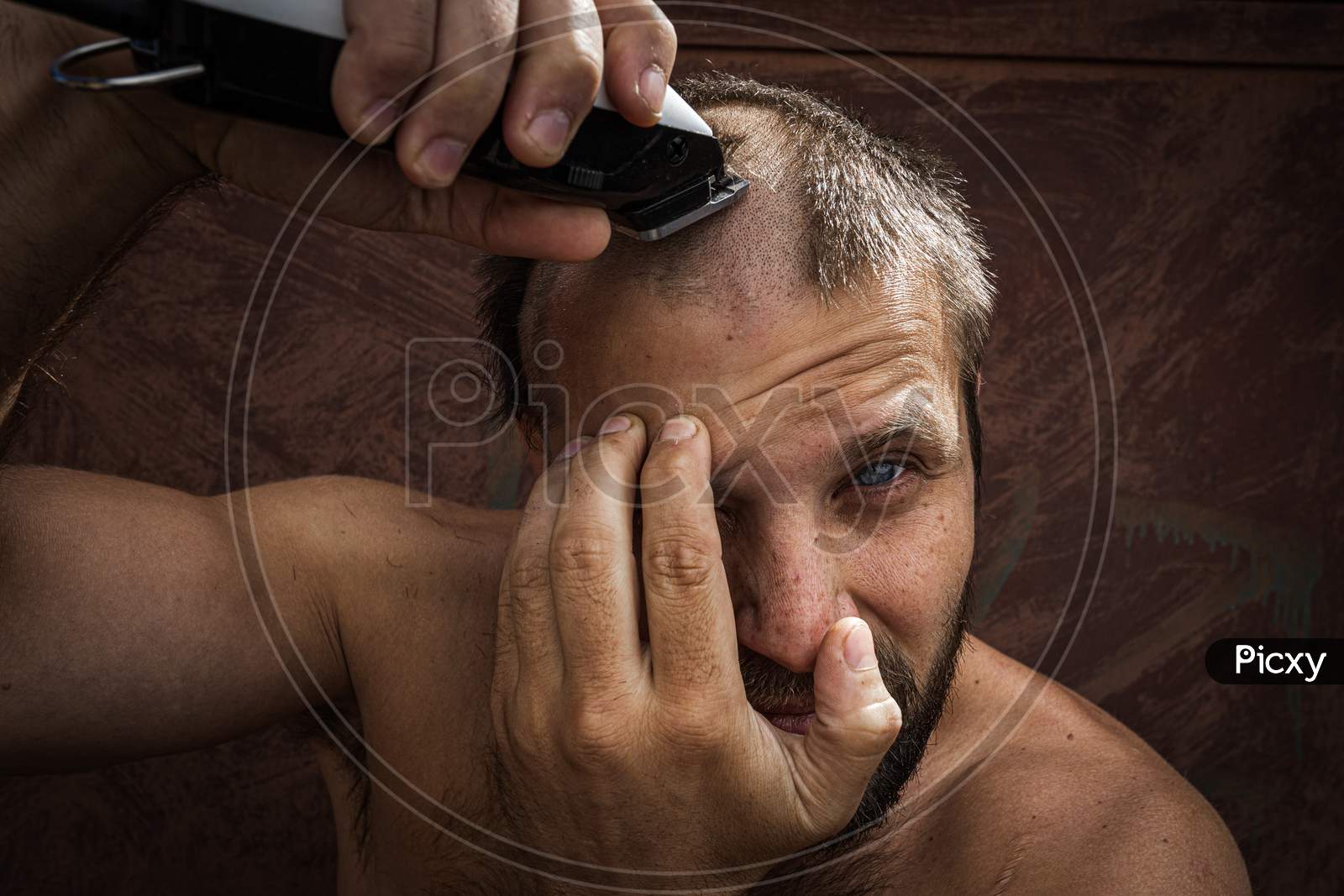 Close-Up Portrait Of Handsome Shirtless Man Shaving His Head With An Electric Razor  Against Brutal Background. Concept Of Male Home Care Without Beauty Salons