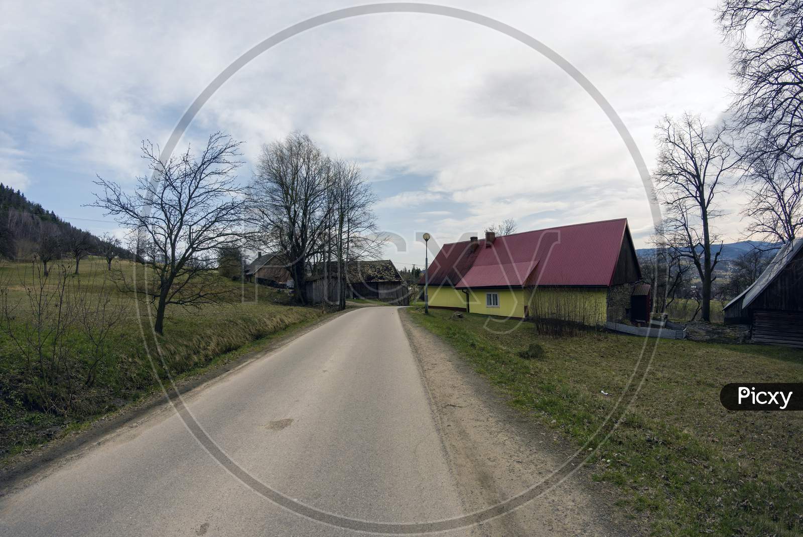 Limanowa, South Poland - April 01, 2021: View Of Country Side Showing Turning Narrow Road With House And Trees Located In Lysa Gora Beskid Wyspowy In The Polish Mountains