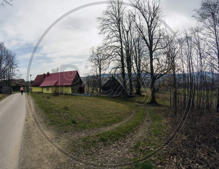 Limanowa, South Poland - April 01, 2021: View Of Country Side Showing Turning Narrow Road With House And Trees Located In Lysa Gora Beskid Wyspowy In The Polish Mountains
