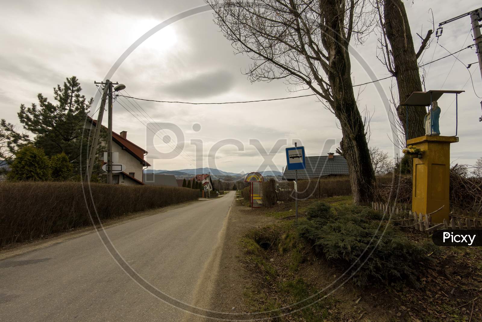 Limanowa, South Poland - April 01, 2021: View Of Country Side Showing Narrow Road And Bus Stop Located In Lysa Gora Beskid Wyspowy In The Polish Mountains