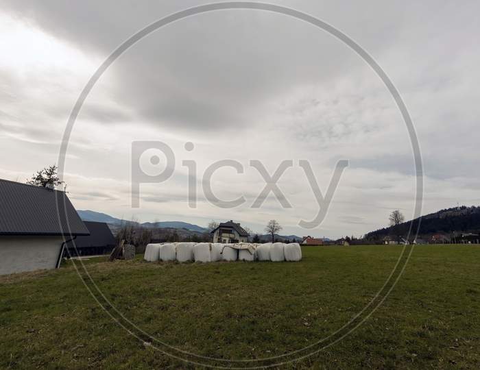 Limanowa, South Poland - April 01, 2021: Wide Angle Shot Of Country Side Showing Stocks Of Covered Hay Crops In The Meadow Country Side Located In Lysa Gora Beskid Wyspowy In The Polish Mountains