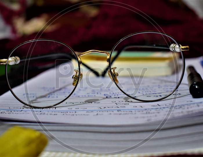 glasses placed on written paper shows some kind of worrk etc