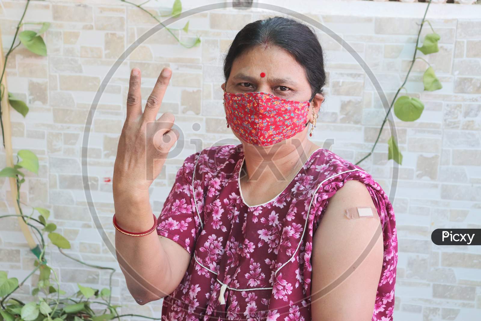 Image of Indian Woman Do Victory Sign After Getting Vaccination During New  Strain Of Covid-19, Mature Woman Wearing Mask With Bandage Applied Received  A Coronavirus Vaccine On Her Arm. Immunization Program.-DB205496-Picxy