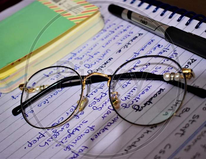 glasses placed on written paper shows some kind of worrk etc