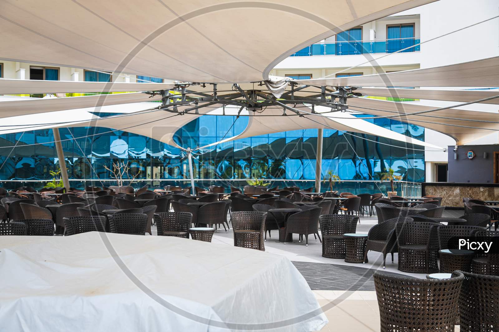 Huge Dining Area With Dark Tables And Chairs Outside Under Huge Umbrellas In The Hotel